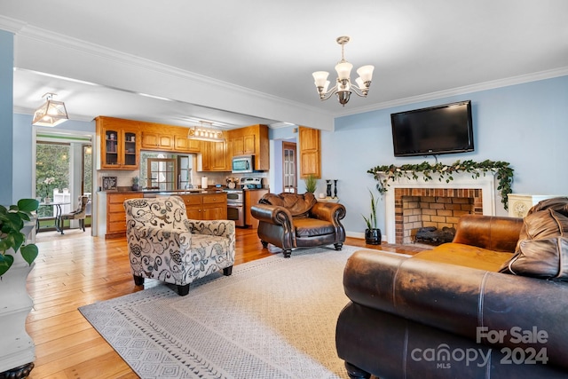 living room featuring a brick fireplace, ornamental molding, a notable chandelier, and light hardwood / wood-style floors