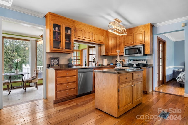 kitchen featuring decorative backsplash, crown molding, light hardwood / wood-style flooring, stainless steel appliances, and a center island