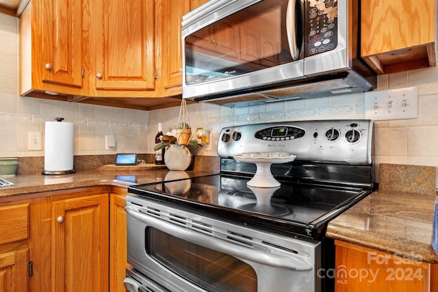 kitchen with stainless steel appliances, light stone countertops, and tasteful backsplash