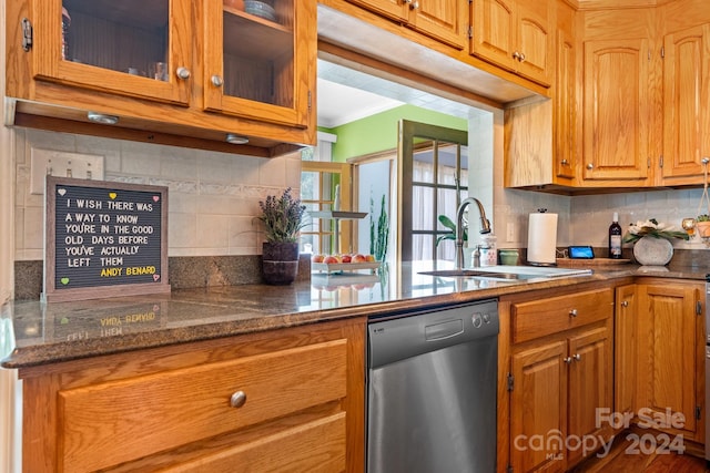 kitchen featuring decorative backsplash, hardwood / wood-style flooring, dark stone countertops, sink, and dishwasher