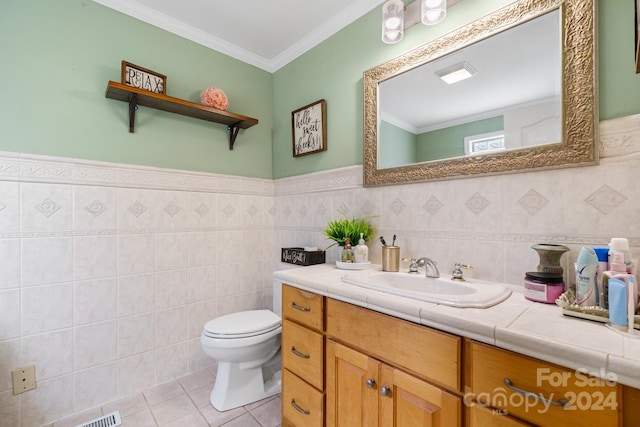 bathroom featuring vanity, ornamental molding, tile patterned floors, tile walls, and toilet