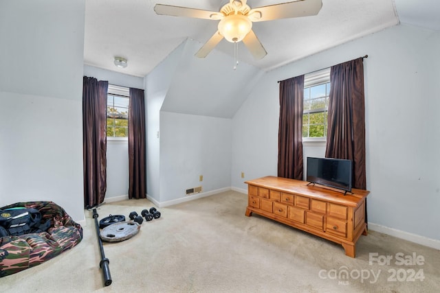 interior space with ceiling fan, a wealth of natural light, vaulted ceiling, and light colored carpet