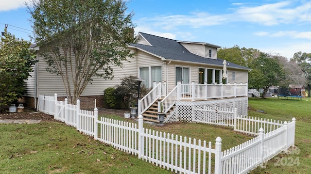 view of front of house with a trampoline, a front yard, and a deck