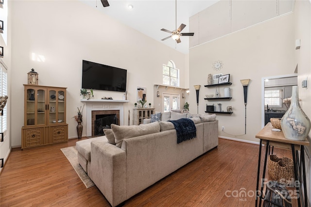 living room with a tile fireplace, high vaulted ceiling, ceiling fan, and hardwood / wood-style flooring