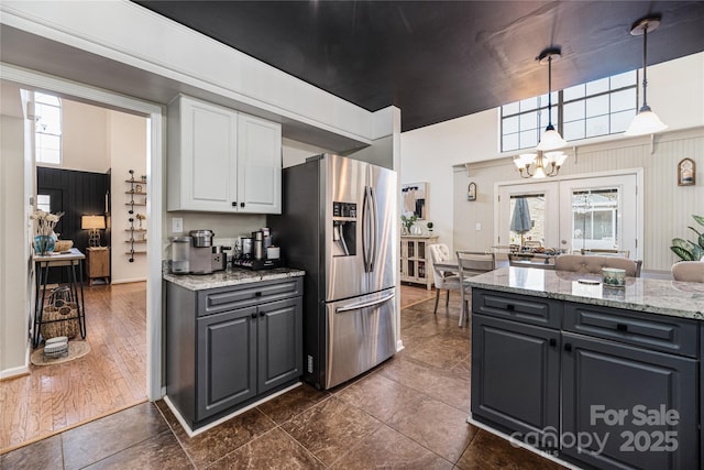 kitchen with gray cabinetry, light stone countertops, stainless steel fridge, pendant lighting, and white cabinetry