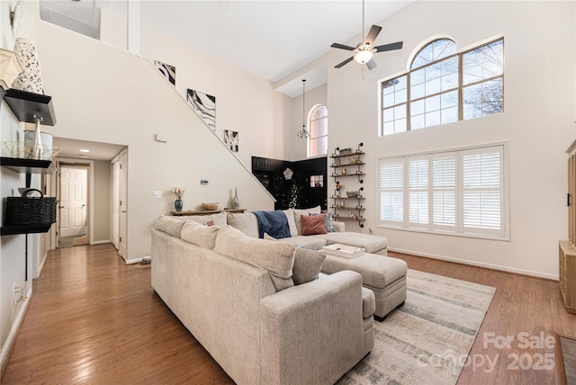 living room with a high ceiling, ceiling fan, hardwood / wood-style flooring, and a healthy amount of sunlight