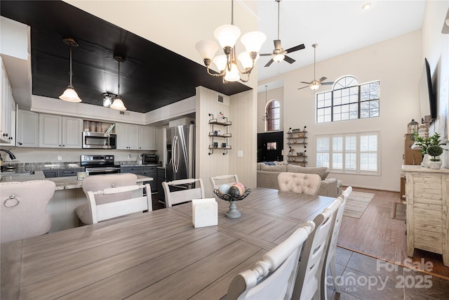 dining space featuring ceiling fan with notable chandelier, hardwood / wood-style floors, and sink