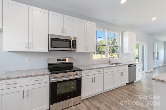 kitchen featuring light hardwood / wood-style floors, appliances with stainless steel finishes, sink, and white cabinetry