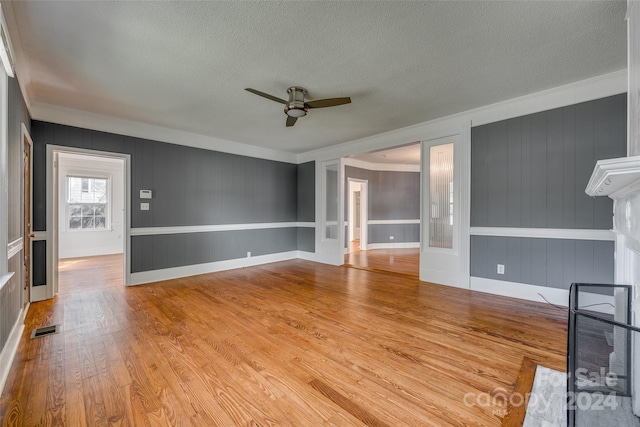 unfurnished living room featuring ceiling fan, a textured ceiling, light hardwood / wood-style flooring, and ornamental molding