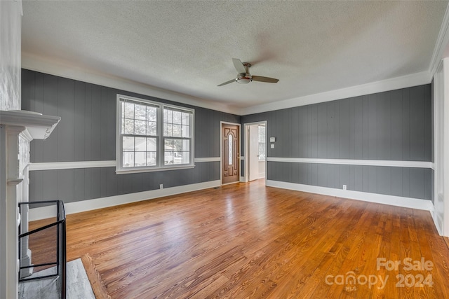 unfurnished room featuring wood-type flooring, a textured ceiling, wood walls, and ceiling fan