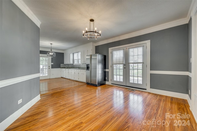 interior space featuring a notable chandelier, light wood-type flooring, crown molding, and a textured ceiling