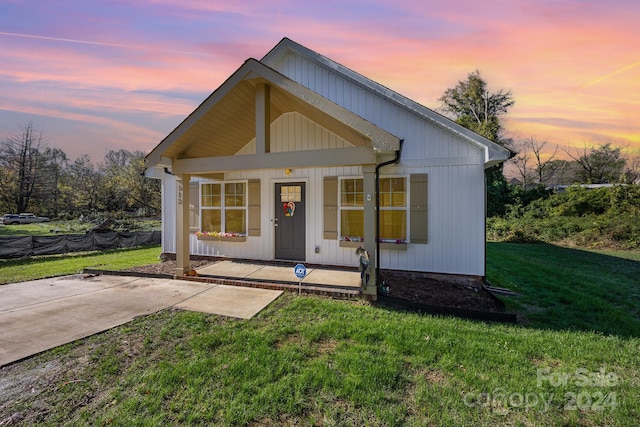 view of front of property featuring covered porch and a lawn