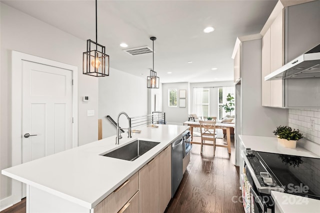 kitchen with an island with sink, sink, dark hardwood / wood-style flooring, hanging light fixtures, and backsplash