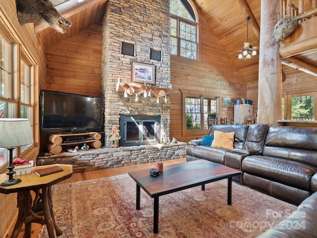 living room with wood-type flooring, wooden walls, high vaulted ceiling, and a wealth of natural light