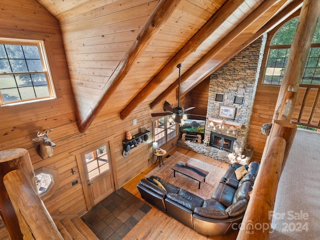 living room with lofted ceiling with beams, a fireplace, a wealth of natural light, and wood walls