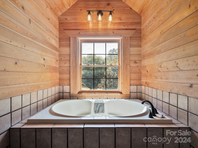 bathroom with wood walls, tiled tub, and vaulted ceiling