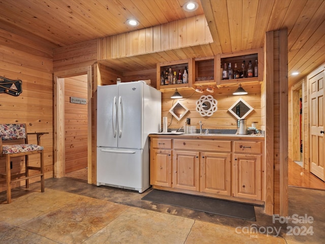 kitchen with white fridge, wood walls, sink, and wood ceiling