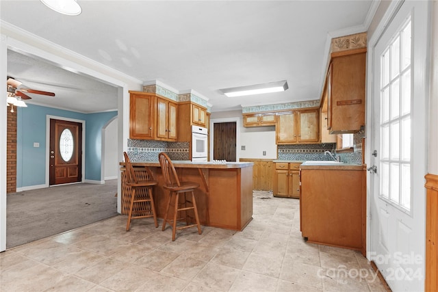 kitchen featuring kitchen peninsula, a wealth of natural light, white oven, and a breakfast bar