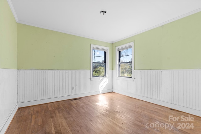 unfurnished room with hardwood / wood-style flooring and crown molding