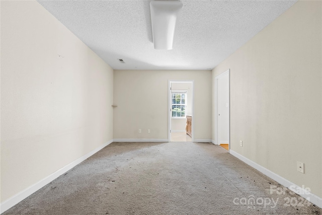 unfurnished room with carpet and a textured ceiling