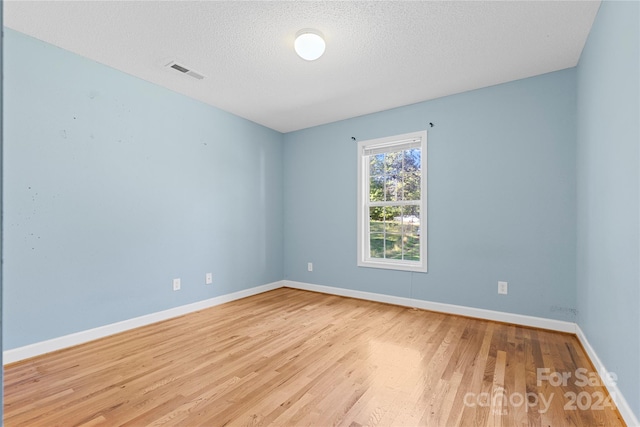 empty room with light hardwood / wood-style floors and a textured ceiling