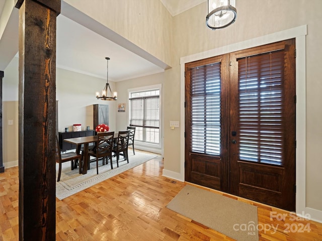 foyer with crown molding, french doors, a chandelier, and light hardwood / wood-style flooring