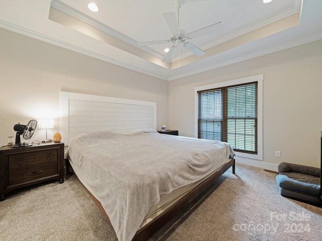 carpeted bedroom with a raised ceiling, ornamental molding, and ceiling fan