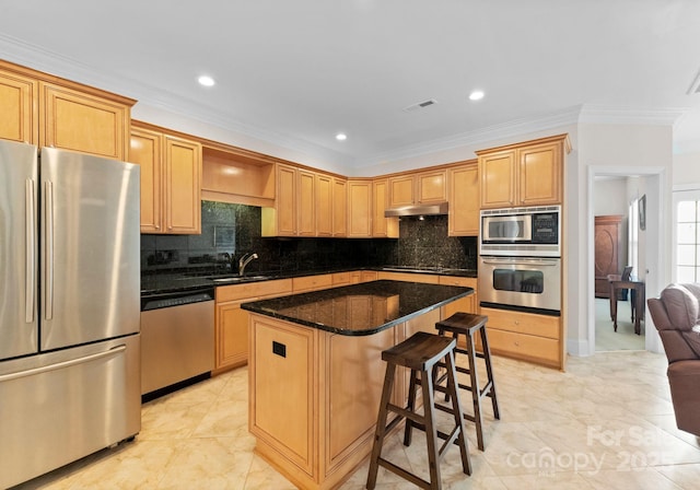 kitchen featuring sink, stainless steel appliances, dark stone counters, a kitchen island, and ornamental molding