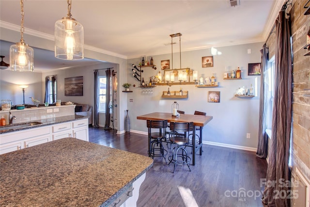 kitchen with white cabinetry, dark hardwood / wood-style flooring, sink, and pendant lighting