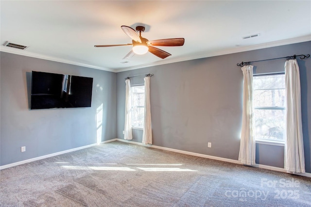 carpeted empty room featuring ceiling fan, crown molding, and a healthy amount of sunlight