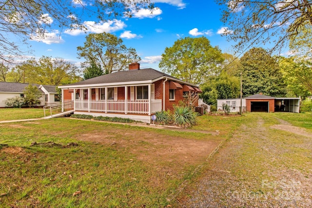 view of front facade with a garage, an outbuilding, a front lawn, and covered porch