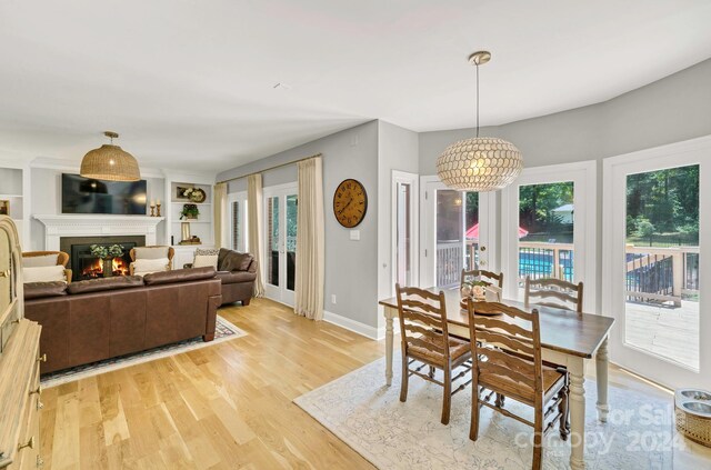 dining space featuring built in shelves, light wood-type flooring, and a chandelier