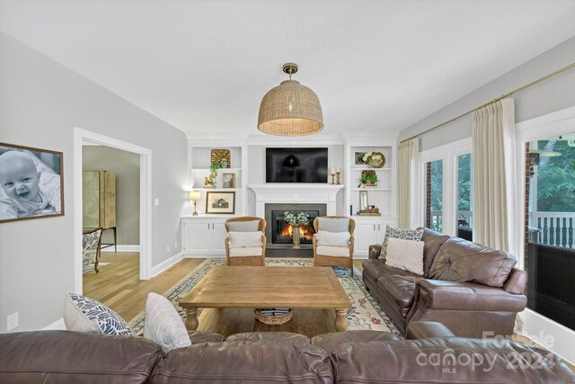 living room featuring built in shelves and light wood-type flooring