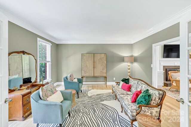 sitting room featuring a fireplace, crown molding, and light wood-type flooring