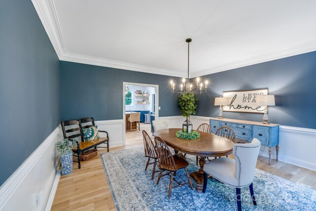 dining room with light hardwood / wood-style floors, crown molding, and a notable chandelier