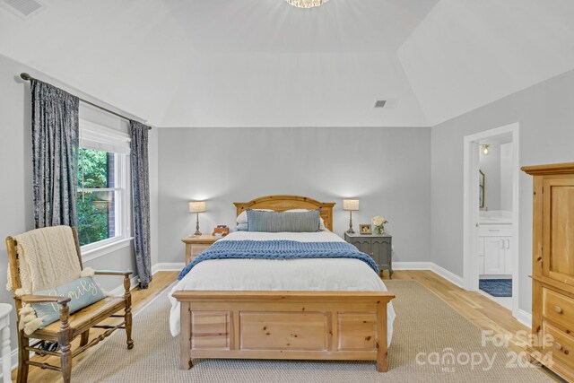 bedroom featuring ensuite bathroom, lofted ceiling, and light wood-type flooring