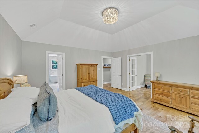 bedroom with light hardwood / wood-style floors, vaulted ceiling, a notable chandelier, and ensuite bath