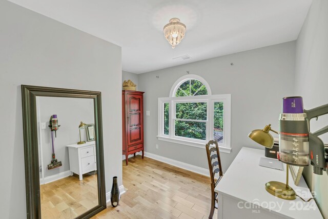 home office with an inviting chandelier and light hardwood / wood-style flooring