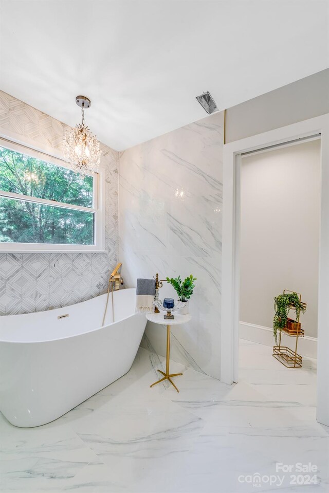 bathroom featuring a notable chandelier, a tub to relax in, and tile walls