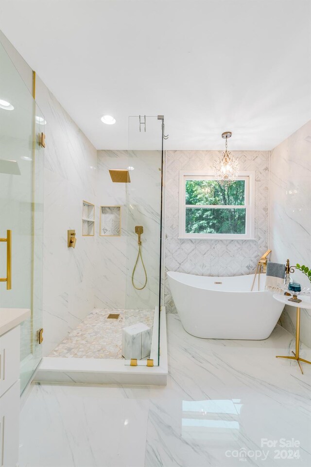 bathroom with a chandelier, vanity, plus walk in shower, and tile walls