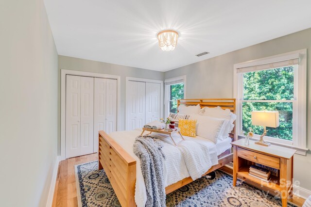 bedroom with light wood-type flooring and two closets