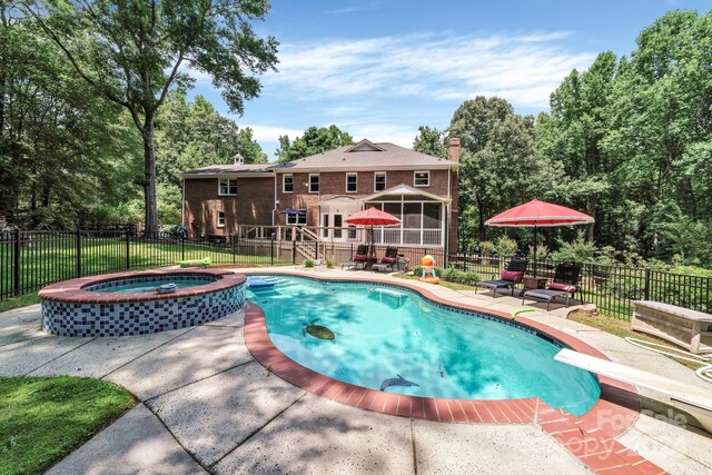 view of swimming pool with a sunroom, a patio, an in ground hot tub, a diving board, and a lawn