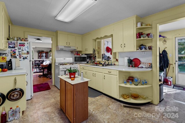 kitchen with a kitchen island, sink, and white appliances