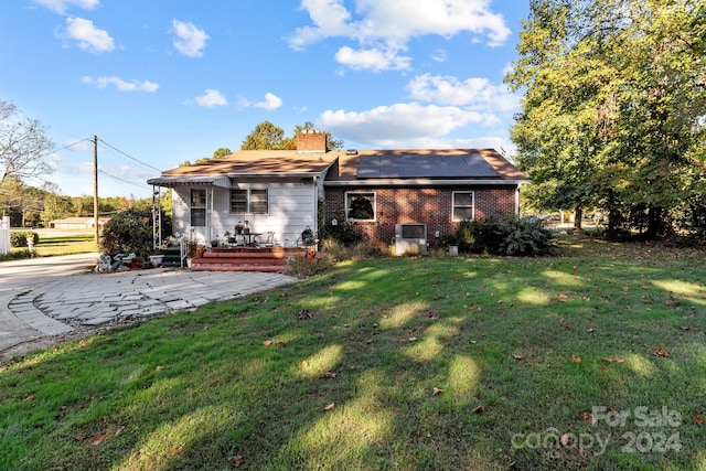 rear view of property with a yard and solar panels