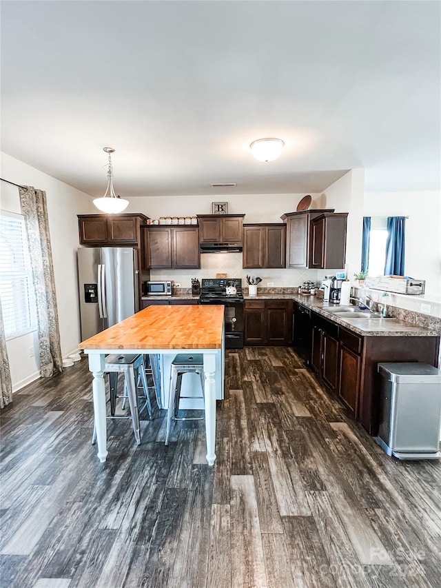 kitchen with sink, hanging light fixtures, dark hardwood / wood-style floors, appliances with stainless steel finishes, and dark brown cabinetry