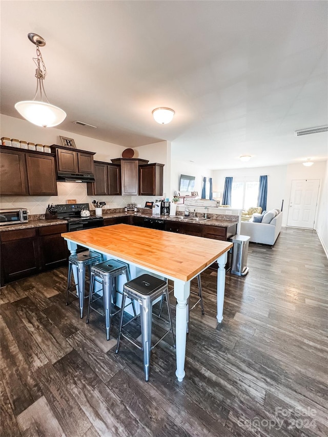 kitchen featuring black electric range, dark brown cabinetry, butcher block countertops, and a breakfast bar area