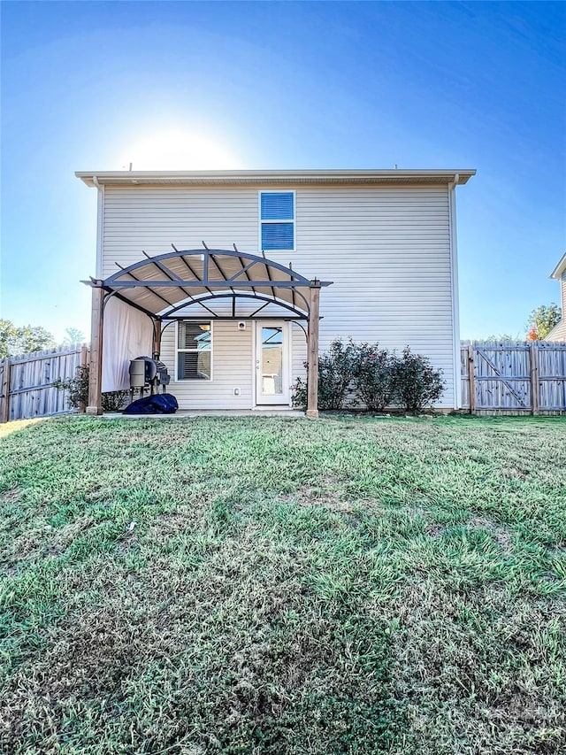 rear view of house featuring a pergola and a lawn