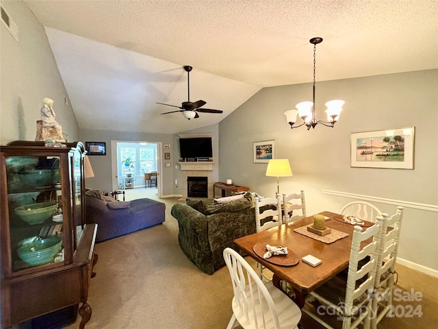 carpeted dining space with lofted ceiling, a textured ceiling, a tile fireplace, and ceiling fan with notable chandelier