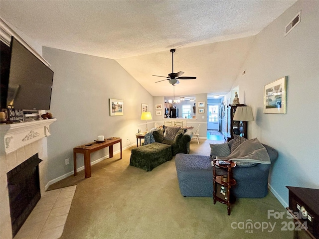 living room featuring lofted ceiling, a tile fireplace, light colored carpet, a textured ceiling, and ceiling fan