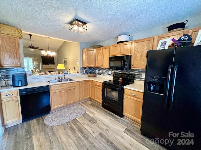 kitchen featuring black appliances, sink, backsplash, lofted ceiling, and decorative light fixtures